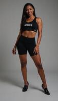 A sultry black female figure with toned abs showcases her muscular physique in a minimalist setting on a monochrome backdrop photo