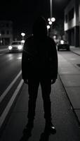 A hooded figure stands on an urban street amidst mysteryevoking blurs of light photo