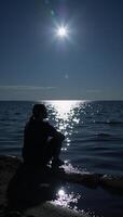 Lone figure contemplates under moonlit sky by waters edge photo