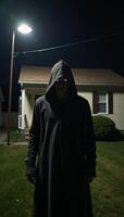 Hooded intruder with glowing eyes tries to break into house at night photo