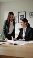 A multicultural female mentor provides guidance to her trainee on business matters within an office setting photo