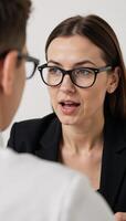 A businesswoman shares strategies with her mentor showcasing an expressive face in a stylish ensemble of black glasses and silver earrings photo