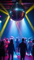 A disco ball illuminates the dancefloor with rainbow beams and swirling bokeh lights behind photo