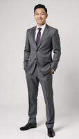 Portrait of an Asian businessman in a grey suit exuding confidence and friendliness against a purewhite backdrop photo