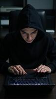 A criminal hacker at work on his laptop ready to commit a cybercrime photo