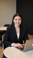 A happy and confident young Latina entrepreneur smiles while working remotely at a cafbar in her stylish business attire as a symbol of modern selfemployment and successful management of a small photo