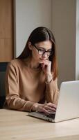A girl with glasses uses her laptop at home photo