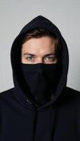 Masked man in dark hoodie with piercing blue gaze photo