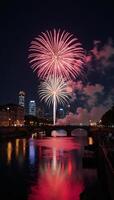 City skyline over river lights up with firework displays during nighttime festivities photo