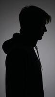 Man silhouetted with hood on dark backdrop anonymous figure in hoodie photo