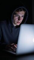 A hacker engages in cybercrime through his laptop on a dark backdrop while a young hacking prodigy battles him in an Internet Security Standoff photo