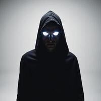 Hooded figure with glowing eyes silhouetted against a dark backdrop photo