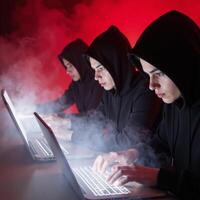 Three cloaked figures hack anonymously within a sinister digital lair photo