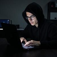 A criminal hacker at work on his laptop ready to commit a cybercrime photo
