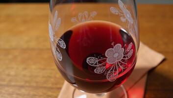 Red wine glass with filled contents on table photo