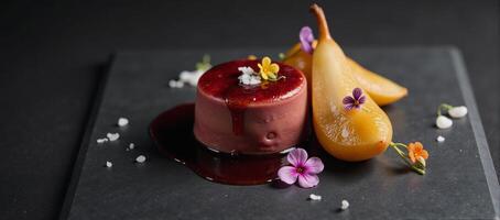 Luxurious foie gras dish with caramelized pear red wine reduction edible flowers and sea salt presented on sleek black slate photo
