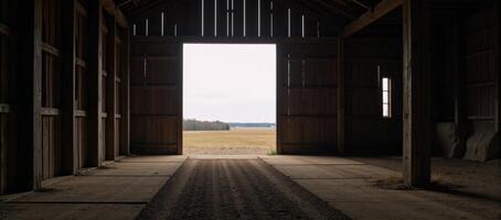 Large empty barn featuring an illuminated entranceway photo