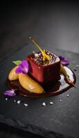 Luxurious foie gras dish with caramelized pear red wine reduction edible flowers and sea salt presented on sleek black slate photo