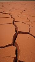 Craggy weathered landscape featuring cracked red soil and strewn rocks photo