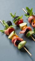Bitesized prosciutto blackberry cucumber arugula skewer on a grey backdrop photo
