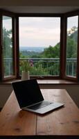 Laptop on wood table with balcony dusk view photo