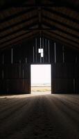 Large empty barn featuring an illuminated entranceway photo