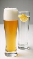 A Hefeweizen glass holds a hazy golden beer while another is garnished photo