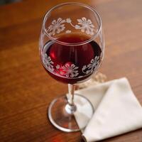 Red wine glass with filled contents on table photo