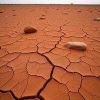 Craggy weathered landscape featuring cracked red soil and strewn rocks photo