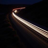 Fastmoving train trail lights across dark night road photo