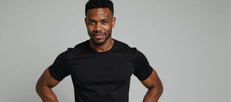 A confident AfricanAmerican model showcases the flexibility of a fitted black tee on a neutral backdrop photo