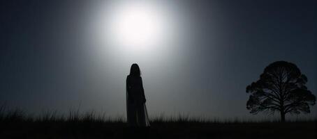 Ghostly figure depicted as silhouette against a lit night sky with a full moon over an open field photo
