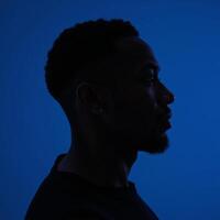 Outline of an AfricanAmerican man in profile against deep blue backdrop photo