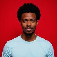 An African American man with an Afro stands against a red backdrop photo