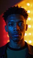 Portrait features a young African American man with geometric facial structure against a backdrop of vibrant neon colors photo