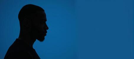 Outline of an AfricanAmerican man in profile against deep blue backdrop photo