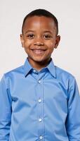 Portrait of a young AfricanAmerican boy smiling gently in a blue shirt against a pure white backdrop photo