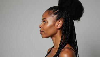 A beautiful Black African American woman with curly long braids and a bun displaying a perfect facial structure including a striking sharply defined jawline as she looks to the left in a side profile photo