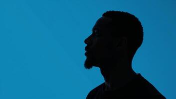 Outline of an AfricanAmerican man in profile against deep blue backdrop photo