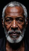 Intense closeup portrait of a wise confident black elder with a gray beard against a dark backdrop photo