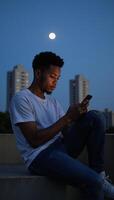AfricanAmerican teen converses on cellphone under moonlit sky photo