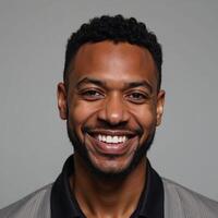 A beaming African American man exudes warmth and charisma against a neutral backdrop photo
