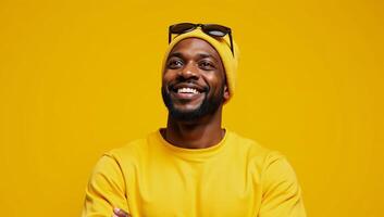 Optimistic Black Man in yellow beanie sweatshirt points upward against bright yellow backdrop Advertising wallpaper mockup featuring African American male photo