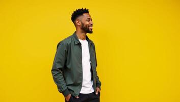 A cool stylish Gen Z black hipster stands on a bright yellow backdrop gazing off into ad space with a happy expression photo
