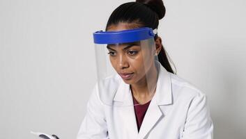 An AfricanAmerican woman worker wears a face shield at work for safety and health care compliance photo