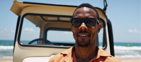 Young African American traveler with sunglasses stands by the seashore car photo