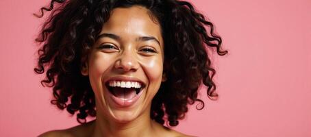 Portrait of laughing AfricanAmerican woman with curly hair against a pink backdrop photo