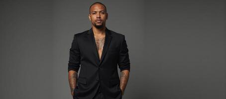Black studio portrait Tattooed man in black suit gazes seriously into the camera his body art on display against a monochrome backdrop photo