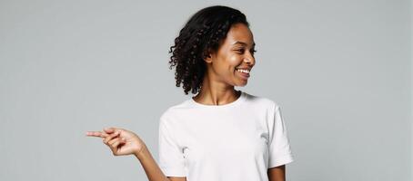 A youthful Black woman smiles in a white tee and points on light gray backdrop perfect mockup for ad designs photo