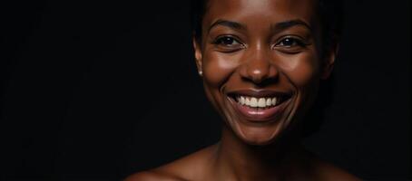 Closeup portrait of a youthful radiant African American woman with smooth skin and a bright smile gazing off into the distance on a dark backdrop photo